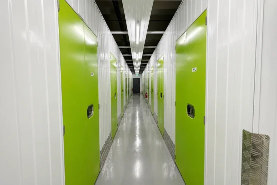 Clean air-conditioned self-storage corridor with green storage unit doors at EBC Lifestyle Hub Singapore.